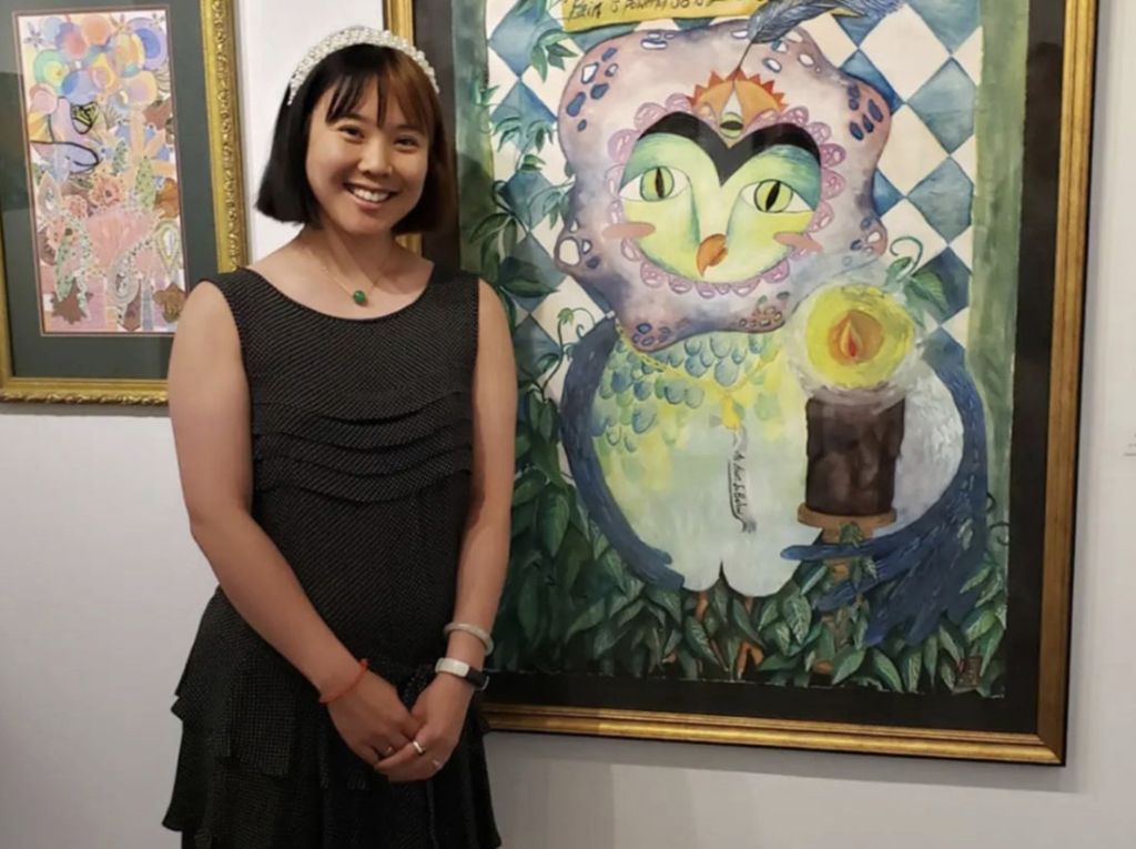 Momentum artist Emily Mah stands in front of her painting